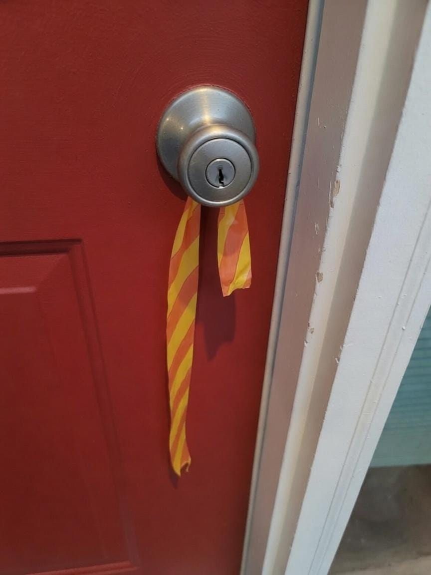 Red and yellow striped evacuation ribbon tied to my front door knob