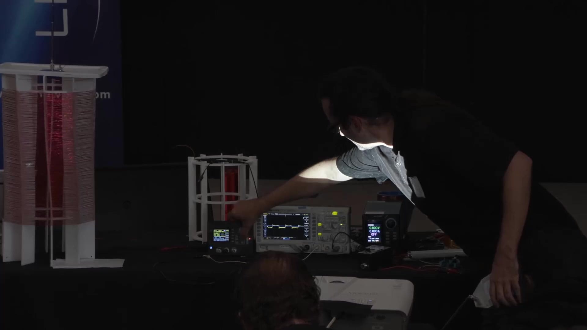 Hakasays at the bench with signal generator and oscilloscope, characterizing the coil wound during the conference